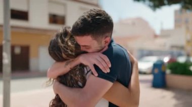 Young hispanic couple smiling confident hugging each other at street
