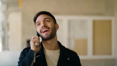 Genç İspanyol adam gülümsüyor. Kendine güveniyor. Sokakta akıllı telefondan konuşuyor.