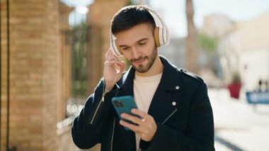 Sokakta müzik dinlerken kendinden emin gülümseyen İspanyol genç adam.