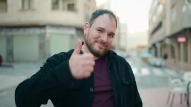 Genç ve cüsseli bir adam gülümsüyor. Kendine güveniyor.