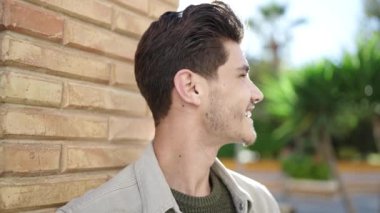 Young hispanic man smiling confident looking to the side at street