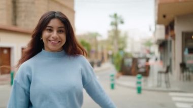Genç İspanyol kadın gülümsüyor. Sokakta dans ediyor.