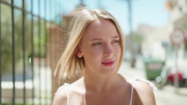 Young blonde woman smiling confident looking to the side at street