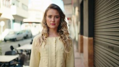 Sokakta kendine güvenen genç sarışın kadın gülümsüyor