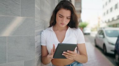 Sokakta dokunmatik ped kullanan genç İspanyol kadın gülümsüyor.