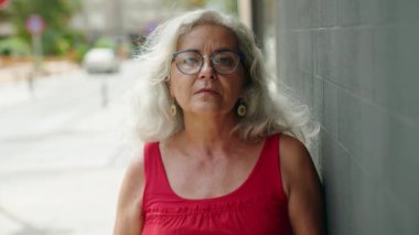 Orta yaşlı, kır saçlı, gülümseyen, kendine güvenen bir kadın.