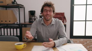 Young hispanic man business worker smiling confident speaking at office