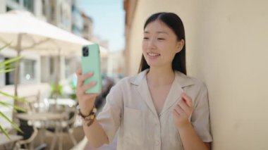 Çinli bir kadın sokakta video araması yaptığından emin gülümsüyor.