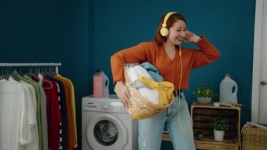 Çamaşır odasında elinde sepetle müzik dinleyen genç kızıl saçlı kadın.