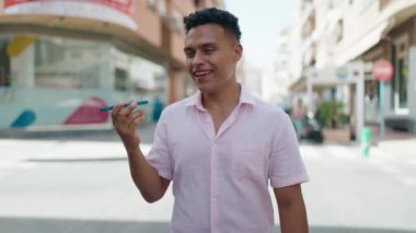 Young latin man smiling confident talking on the smartphone walking at street