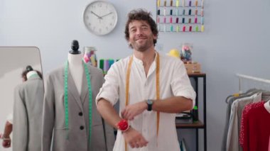 Genç İspanyol terzi gülümsüyor. Giysi fabrikasında kollarını kavuşturmuş duruyor.