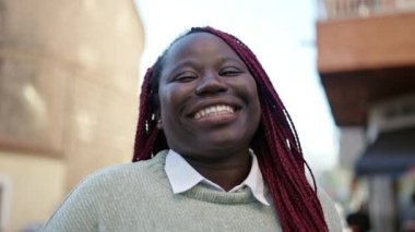 Saçları örgülü, sokakta kendine güvenen Afrikalı bir kadın.