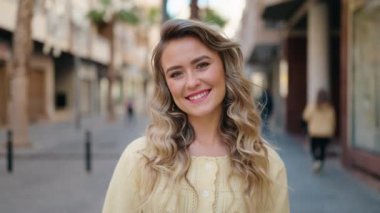 Genç sarışın kadın gülümsüyor. Kendinden emin bir şekilde merhaba diyor.