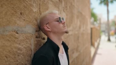 Sokakta ciddi bir ifadeyle duran beyaz bir genç.