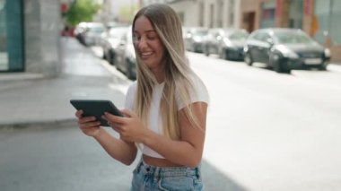 Genç, güzel, İspanyol bir kadın, gülümsüyor. Touchpad 'de videolar seyrediyor.