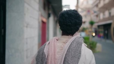 Genç Afro-Amerikan kadın gülümseyerek sokakta yürüyor.