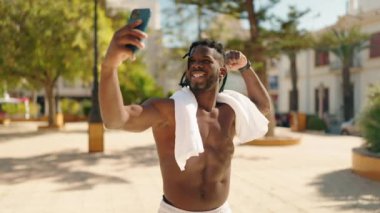 Afro-Amerikan kadın üstsüz, gülümseyen, kendine güvenen, parktaki akıllı telefondan selfie çeken.