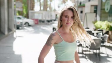 Kahvecinin terasında kendinden emin gülümseyen genç sarışın kadın.