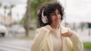 Sokakta müzik dinlerken kendinden emin gülümseyen genç bir kadın.