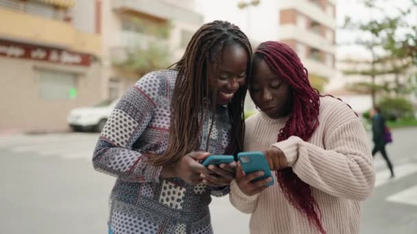 两名非洲裔美国妇女在街上用智能手机充满自信地微笑 — 图库视频影像
