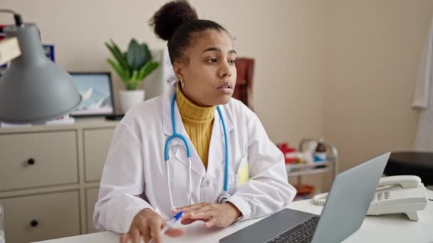 Νεαρή Αφροαμερικανίδα Γιατρός Χρησιμοποιώντας Φορητό Υπολογιστή Κρατώντας Σημειώσεις Στην Κλινική — Αρχείο Βίντεο