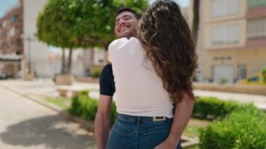 Young hispanic couple smiling confident hugging each other at park