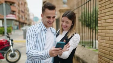 Man and woman couple hugging each other using smartphone at park