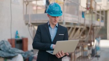 Young caucasian man architect with relaxed expression using laptop at street