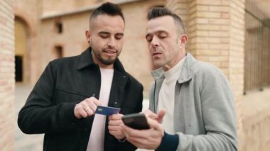 Sokakta akıllı telefon ve kredi kartı kullanan genç çift.