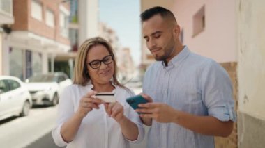 Kadın, erkek, anne ve kız akıllı telefon ve kredi kartı kullanıyor.