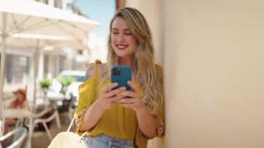 Sokakta akıllı telefon kullanan kendine güvenen genç bir kadın.