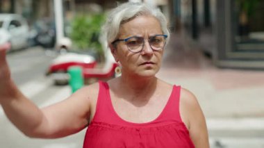 Orta yaşlı, kır saçlı kadın, sokağın aşağısında 