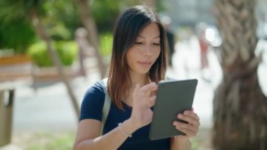 Young asian woman smiling confident using touchpad at street