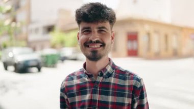 Young hispanic man smiling confident doing kiss gesture with hand at street