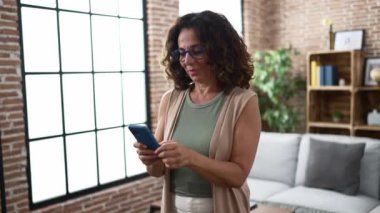 Middle age hispanic woman using smartphone