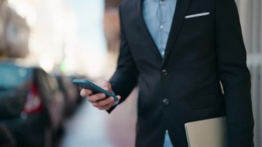 Beyaz bir adam sokakta dizüstü bilgisayar kullanıyor.