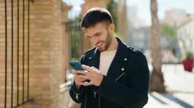Sokakta akıllı telefon kullanan, kendine güvenen genç bir İspanyol.