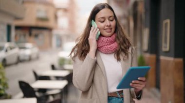 Sokakta dokunmatik ped kullanan akıllı telefondan konuşan genç bir kadın.