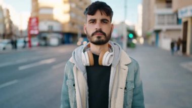 Sokakta kulaklık takarak gülümseyen İspanyol genç adam.