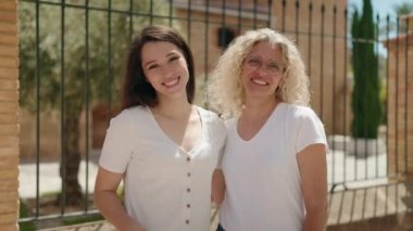 Two women mother and daughter hugging each other and kissing at street