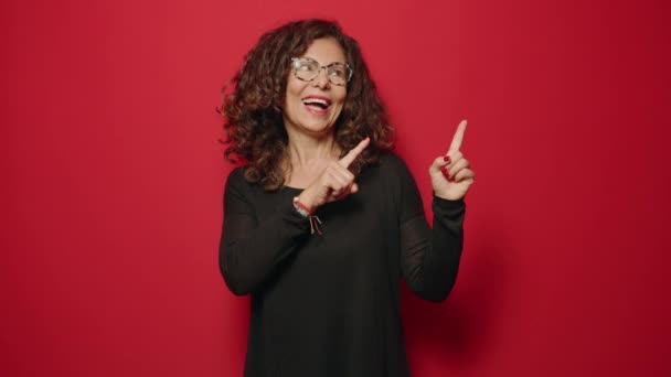 Жінка Середнього Віку Посміхається Впевнено Вказуючи Пальцями Червоний Фон — стокове відео