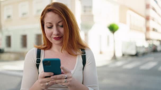Νεαρή Κοκκινομάλλα Γυναίκα Χαμογελά Αυτοπεποίθηση Χρησιμοποιώντας Smartphone Στο Δρόμο — Αρχείο Βίντεο