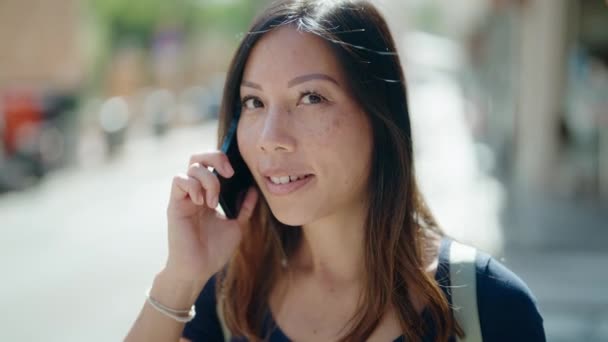 若いアジアの女性は自信を持って話して笑顔路上でスマートフォン — ストック動画