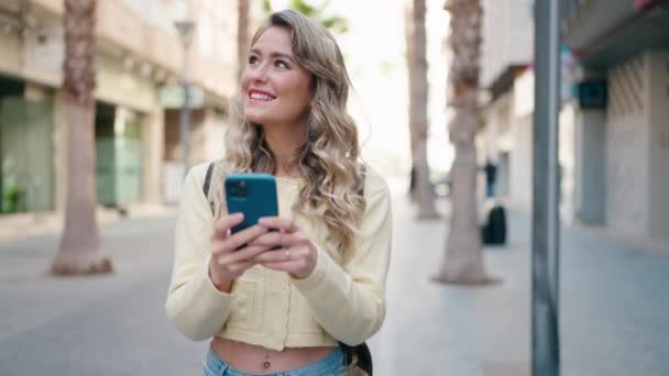 Joven Mujer Rubia Turista Sonriendo Confiado Usando Teléfono Inteligente Calle — Vídeo de stock