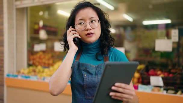 Young Chinese Woman Employee Talking Smartphone Using Touchpad Fruit Store — Stock video