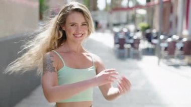 Sokakta kollarını kavuşturmuş genç sarışın kadın.