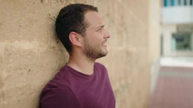 Young man with relaxed expression standing over isolated brick background