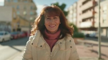 Middle age redhead woman smiling confident walking at street