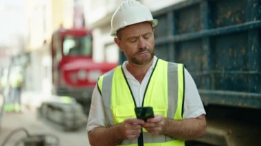 Sokaklarda akıllı telefon kullanan orta yaşlı bir mimar.