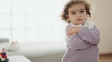 Adorable hispanic girl standing with arms crossed gesture at home